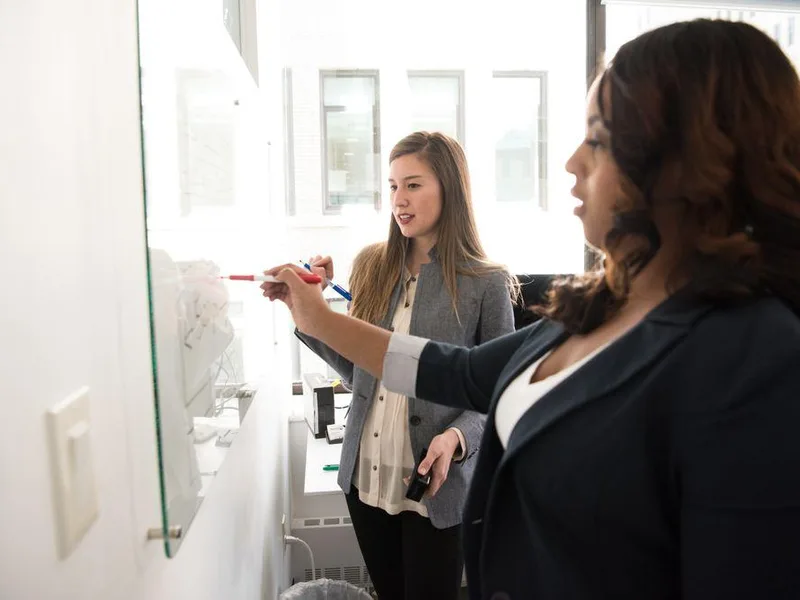 Two colleagues planning together on an office whiteboard