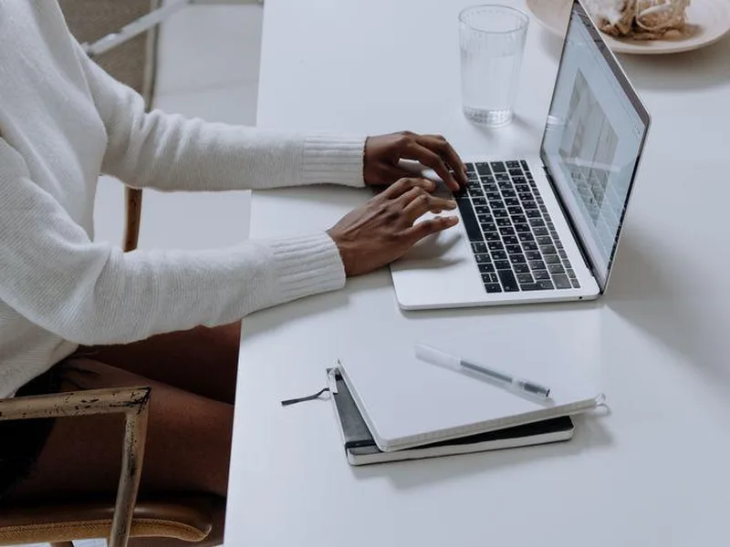 Person working on a laptop at a clean white desk